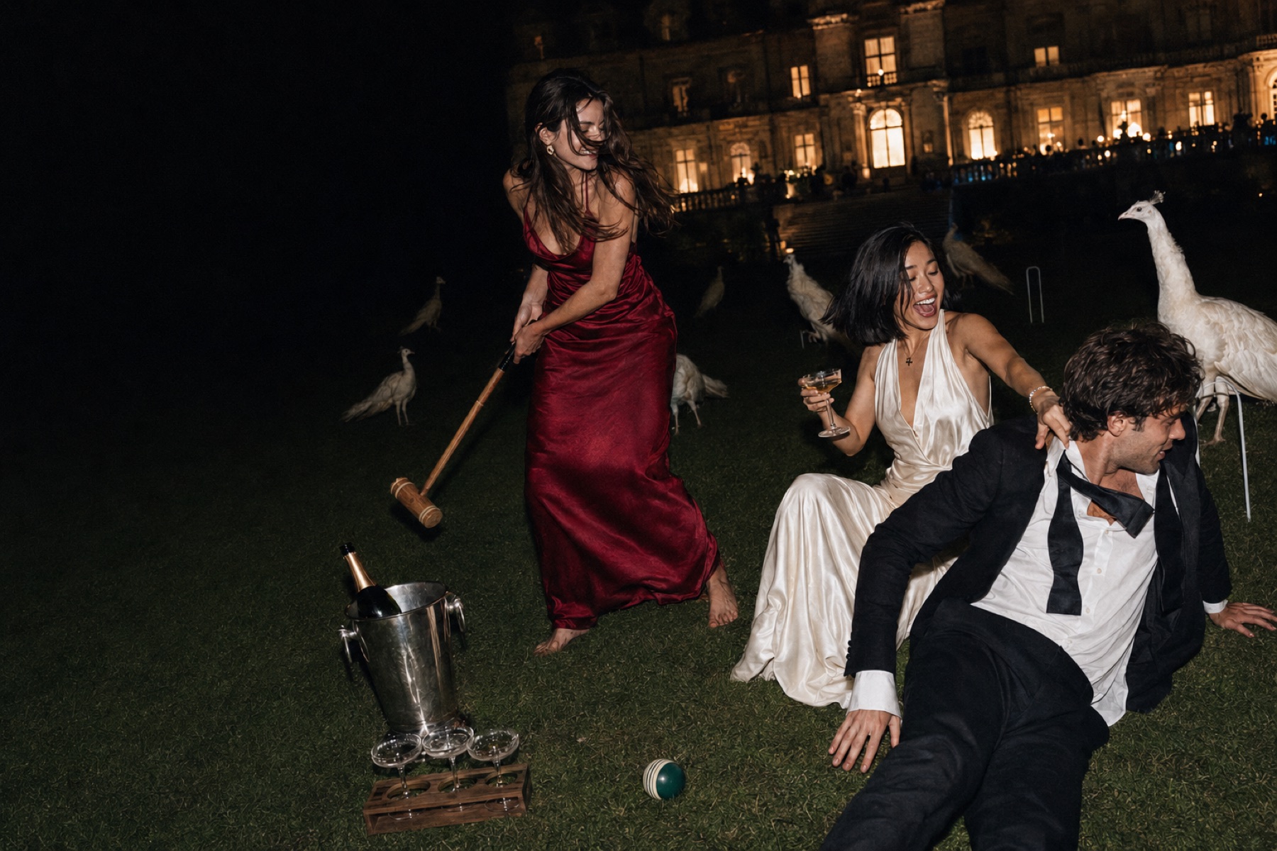 Friends playing croquet on a floodlit lawn at night